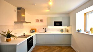 Une cuisine moderne avec des armoires blanches, une hotte de cuisinière en acier inoxydable, un four à micro-ondes et un évier.
