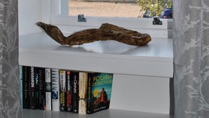 A window with a view of trees, a white shelf with books, and a decorative branch. - Mariners Retreat- spacious apartment in Crail (Crail)