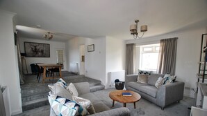 A spacious living area with grey sofas, a wooden coffee table, and a dining table. - Mariners Retreat- spacious apartment in Crail (Crail)