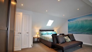 A bedroom with a bed, a sofa, a painting, and a door.