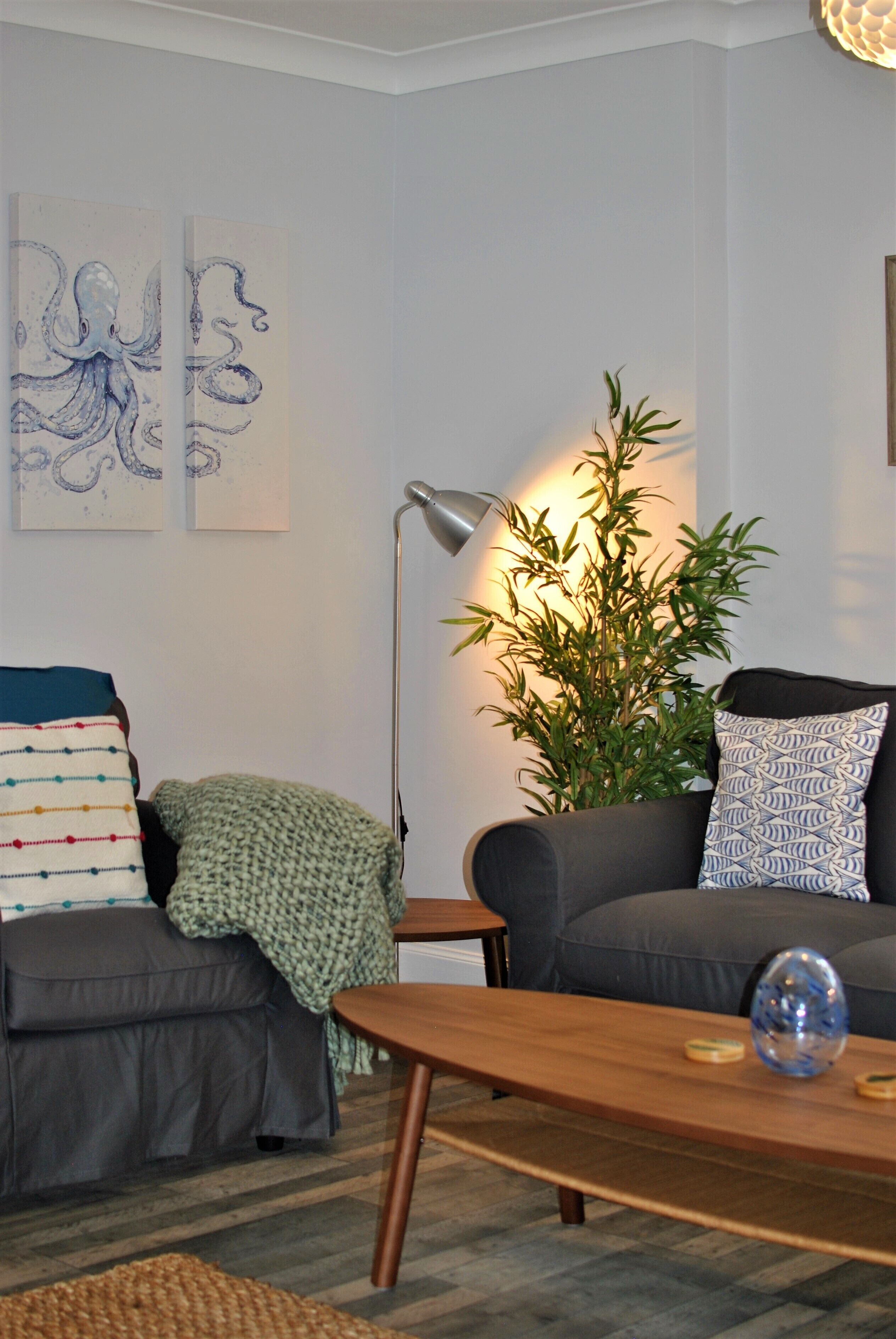 A living room with two sofas, a coffee table, a floor lamp, and wall art.