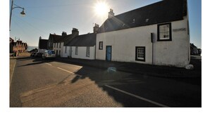 A white building with a blue door, labeled "SHOREGATE," on a street with parked cars. - One Shoregate- cosy Crail retreat (Crail)