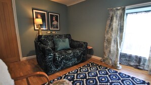 A living room with a patterned sofa, a patterned rug, and a window with curtains. - One Shoregate- cosy Crail retreat (Crail)