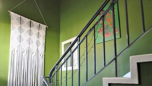 A staircase with a black metal railing and white steps, leading to a room with green walls and a patterned floor. - One Shoregate- cosy Crail retreat (Crail)