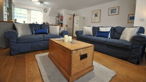 Ein Wohnzimmer mit zwei blauen Sofas, einer Holzkommode und einem weißen Teppich.