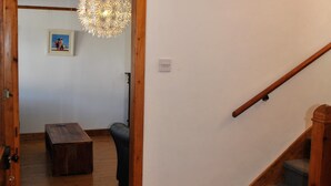 Eine Holztretreppe mit Handlauf, eine Holztür, die in einen anderen Raum führt, und eine Hängelampe.