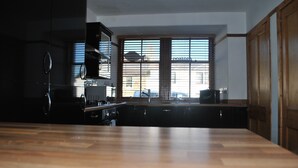Eine moderne Küche mit dunklen Schränken, einer Holz Arbeitsplatte und großen Fenstern, die viel Tageslicht hereinlassen.