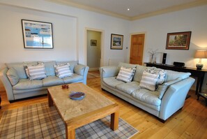 A living room with two light blue leather sofas, a wooden coffee table, and a plaid rug.