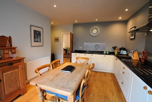 A kitchen with a wooden table, chairs, a clock, and a white cabinet.