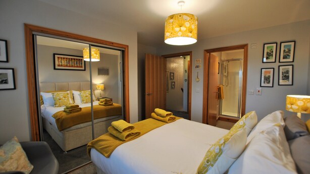 Een hotelkamer met een groot bed, een spiegel, een nachtkastje en een stoel.