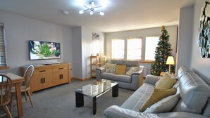 Een woonkamer met een bank, salontafel, televisie en een kerstboom.