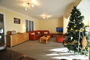 A living room with a sofa, coffee table, TV, and a Christmas tree. - Anchor House Pittenweem - Seaview home (Pittenweem)