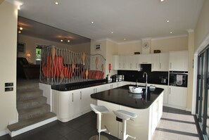 A modern kitchen with white cabinetry, a black countertop, and a unique decorative chair.