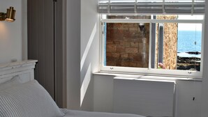 Een slaapkamer met een bed, een raam met uitzicht op zee en een radiator.