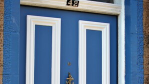 Una puerta azul con marcos blancos, un timbre de latón y un buzón de metal.