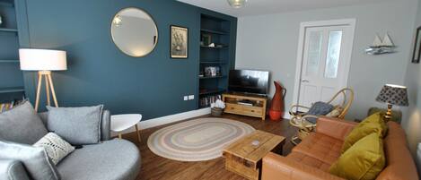 A living room with a sofa, a coffee table, a television, and a bookshelf.