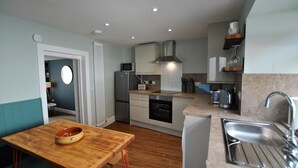 Una cocina funcional con una mesa de madera, un lavamanos y electrodomésticos modernos.