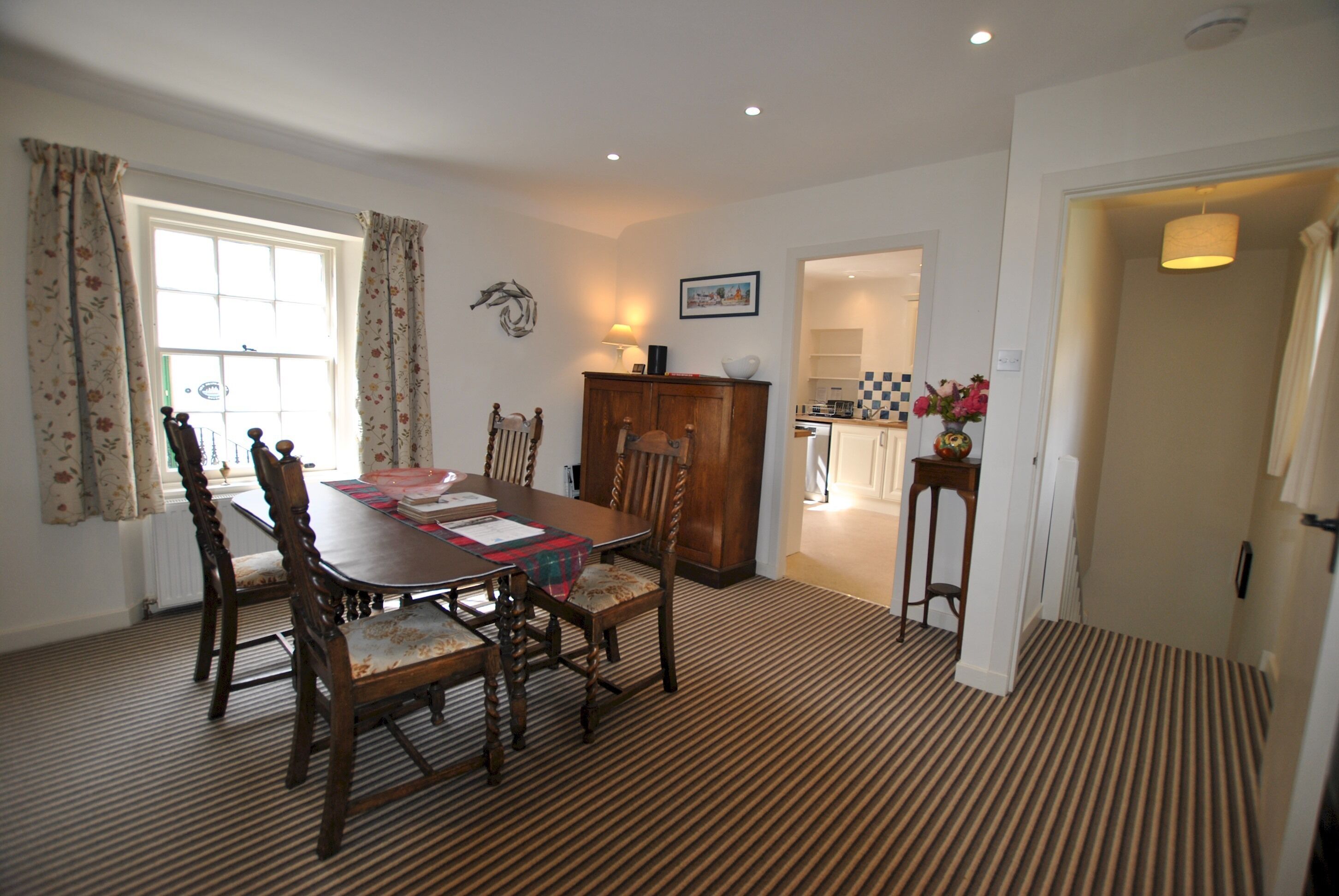 A dining area with a wooden table and chairs, a radiator, and a patterned carpet.