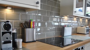 A modern kitchen with grey tiles, stainless steel appliances, and wooden countertops. - Coastal Rest-  superb East Neuk townhouse (Anstruther)