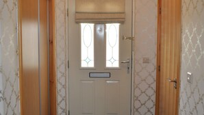 Ein Korridor mit gemustertem Wandpapier, einer Holztür mit Fenster und einer Deckenleuchte.