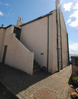 A building with a flat facade, a staircase leading to a door, and a visible manhole cover.