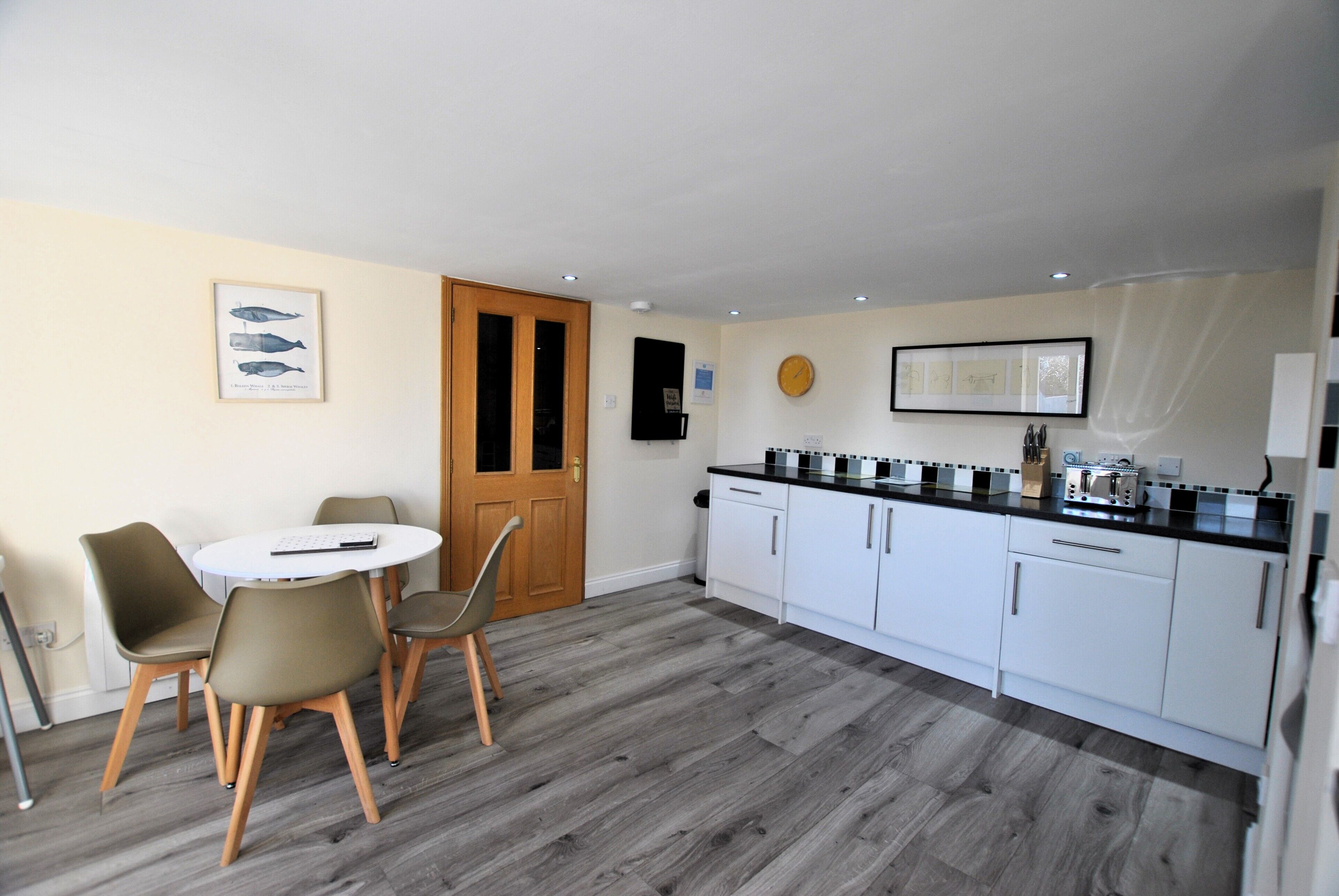 A modern kitchen with white cabinets, a black countertop, and a round dining table with chairs.