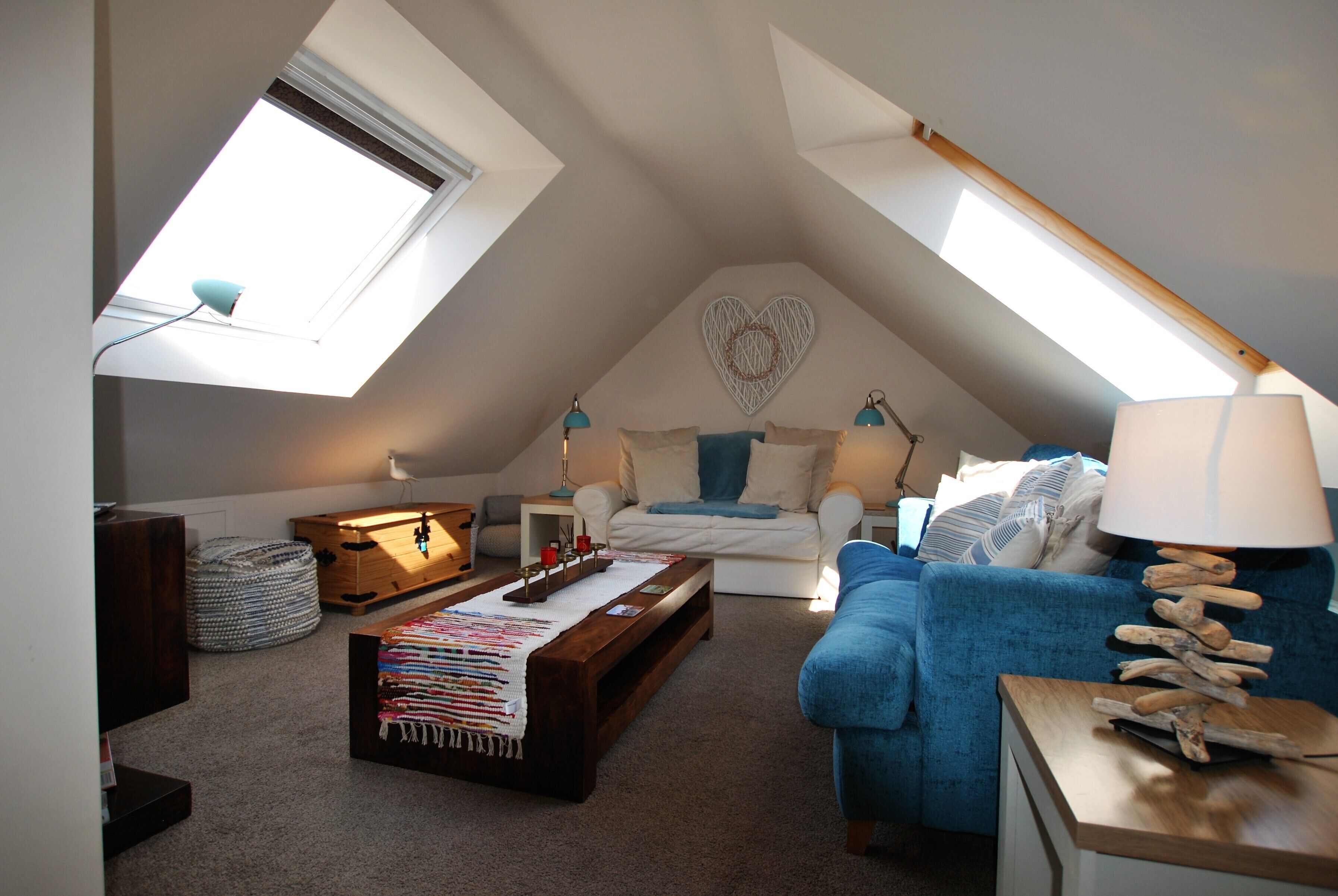 Ein gemütliches Schlafzimmer im Loft-Stil mit schrägem Dach, einer Wanddekoration in Herzform und einem Dachfenster.