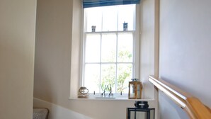 A carpeted staircase with a window above, a lantern, and a small table with decorative items. - Turnstone- beautiful coastal home, Pittenweem (Pittenweem)