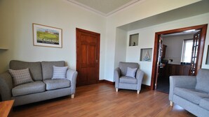 A living room with two grey sofas, a wooden floor, a wooden door, and a framed picture on the wall. - The Beacon-  coastal home in St Monans (Saint Monans)