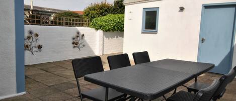 A patio area with a table and chairs, a small window, and a door.