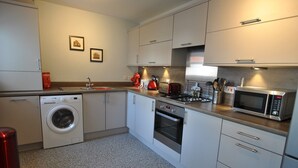 A modern kitchen with a washing machine, oven, microwave, and stainless steel appliances.
