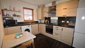 Een moderne keuken met houten kastjes, een magnetron, oven en een spoelbak.