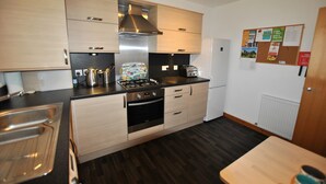 Een moderne keuken met roestvrijstalen apparatuur, houten kastjes en een zwart aanrecht.