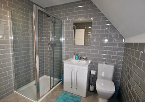 Un baño con cabina de ducha de vidrio, lavabo con alacenas y retrete.