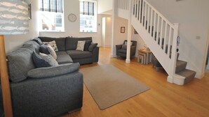 A modern living room with a grey sectional sofa, a small rug, and a staircase leading to an upper level.