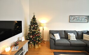 A living room with a Christmas tree, a grey sofa, a flat-screen TV, and a lamp. - Walter's Neuk Anstruther- luxury coastal home (Anstruther)