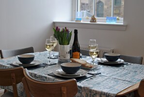 Una mesa de comedor dispuesta con cuencos, copas de vino y una botella.