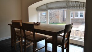 A dining area with a table and chairs, a view of the outside, and a sign indicating 'BEACH'. - Seaview Steading-spacious home in rural location (Crail)