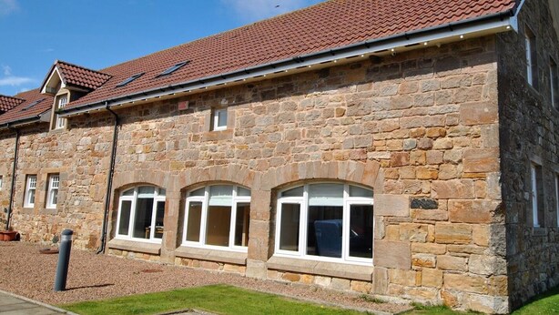 A stone building with a tiled roof, arched windows, and a stone facade. - Seaview Steading-spacious home in rural location (Crail)