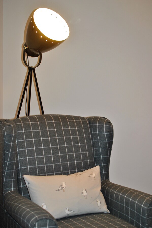 A chair with a checkered fabric and a cushion with bird patterns.
