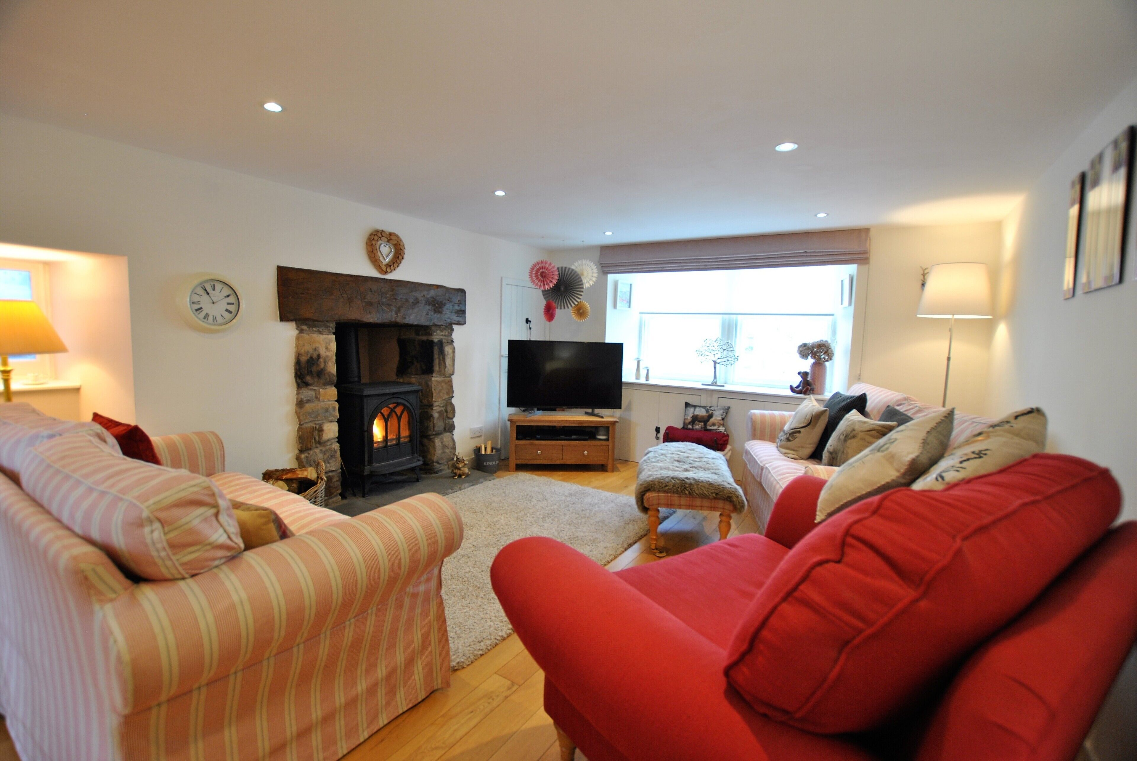 A living room with a fireplace, sofas, a television, and a window with curtains.