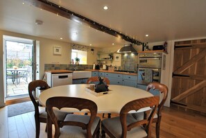 A modern kitchen with a round dining table, wooden chairs, and a built-in oven.