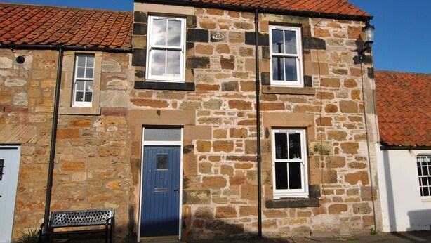 A stone building with a blue door, two windows, and a bench in front. - Willow Cottage- charming cottage in East Neuk (Pittenweem)