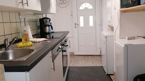 Una cocina con lavamanos, cafetera y refrigerador.