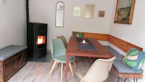 Una habitación acogedora con una mesa de madera, dos sillas, un banco, un sofá, una chimenea y adornos en la pared.