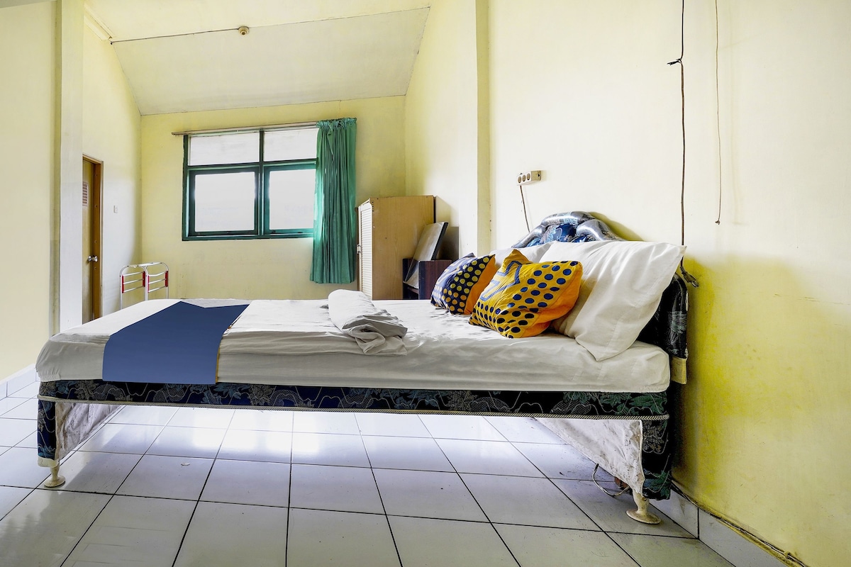 Quarto com cama, janela com cortinas e piso em azulejos.