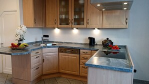 Eine Küche mit Holzausstattung, einem integrierten Geschirrspüler und einer Arbeitsplatte aus Granit.