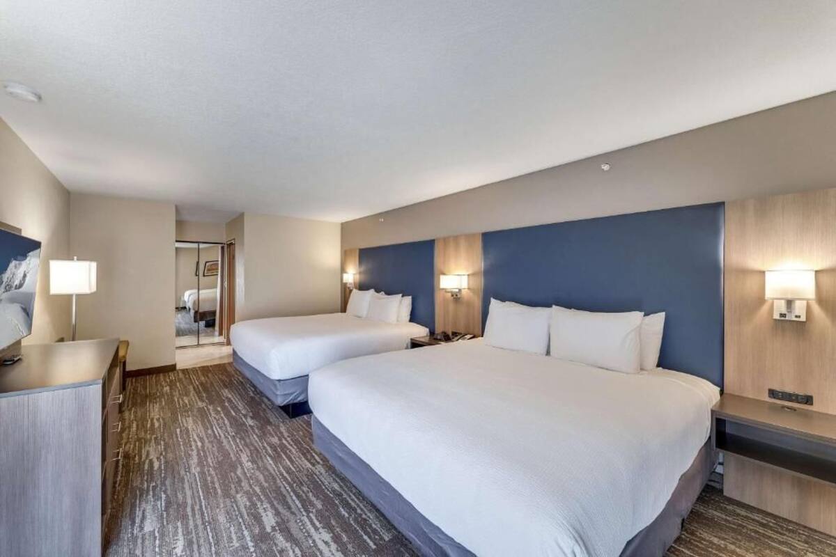 Une chambre d’hôtel avec deux lits, un bureau et un miroir.