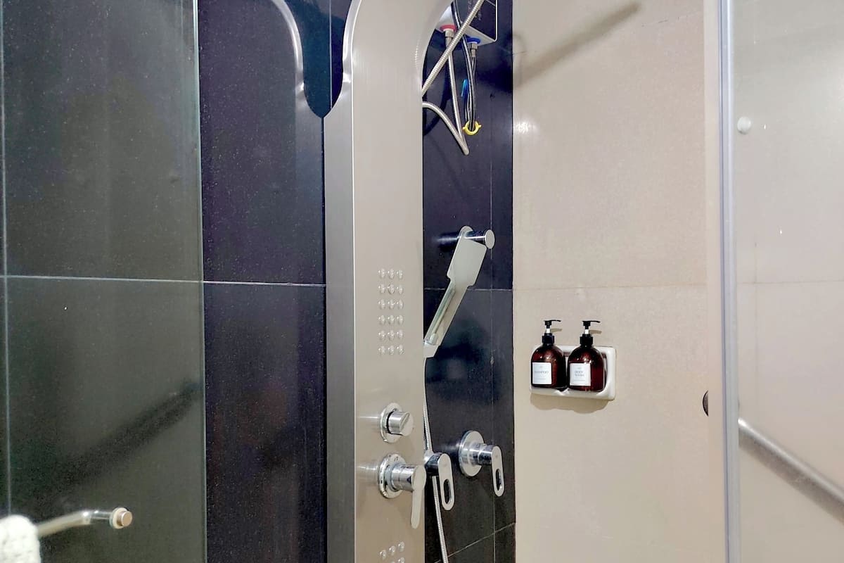 Box de chuveiro com chuveiro manual, um acessório de chuveiro manual e painel de controle fixado na parede.