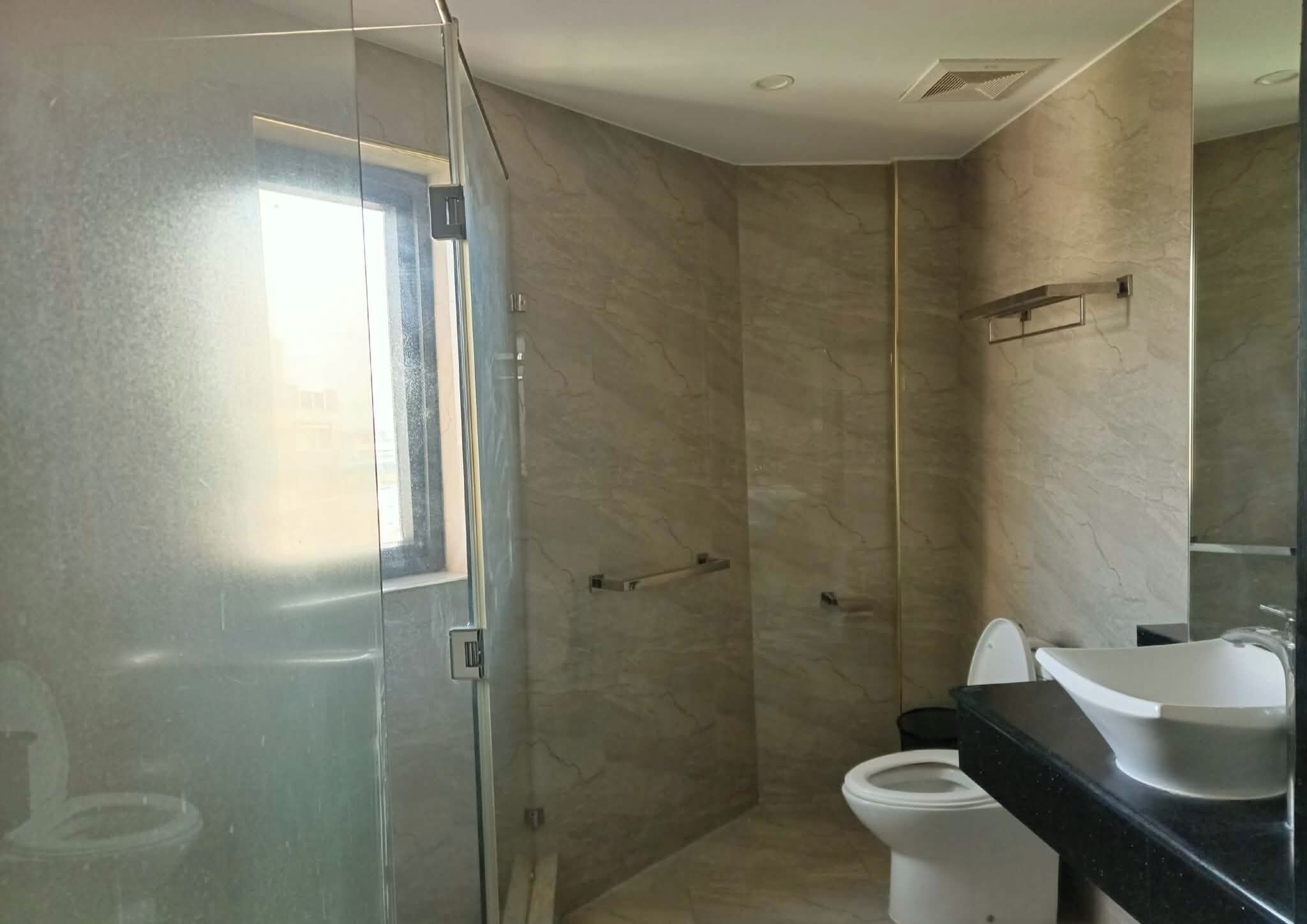 A bathroom with a glass shower enclosure, a toilet, and a sink with a mirror.